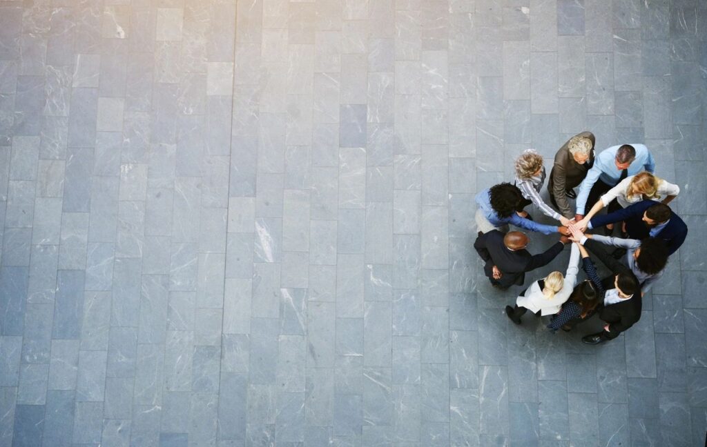 a picture of people standing in s circle with their hands meeting in the middle
