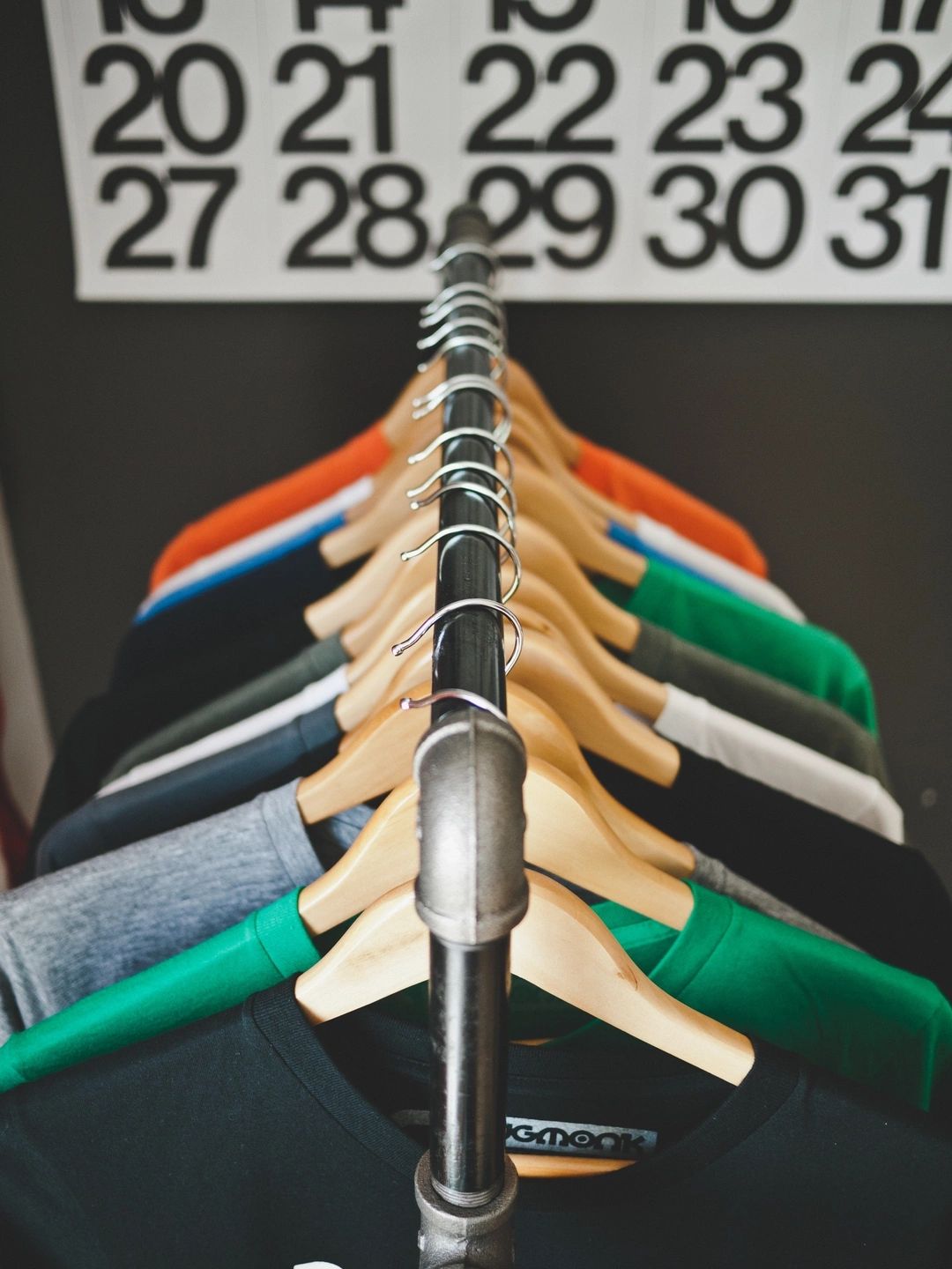 picture of different colored tshirts hanging on wooden hangers