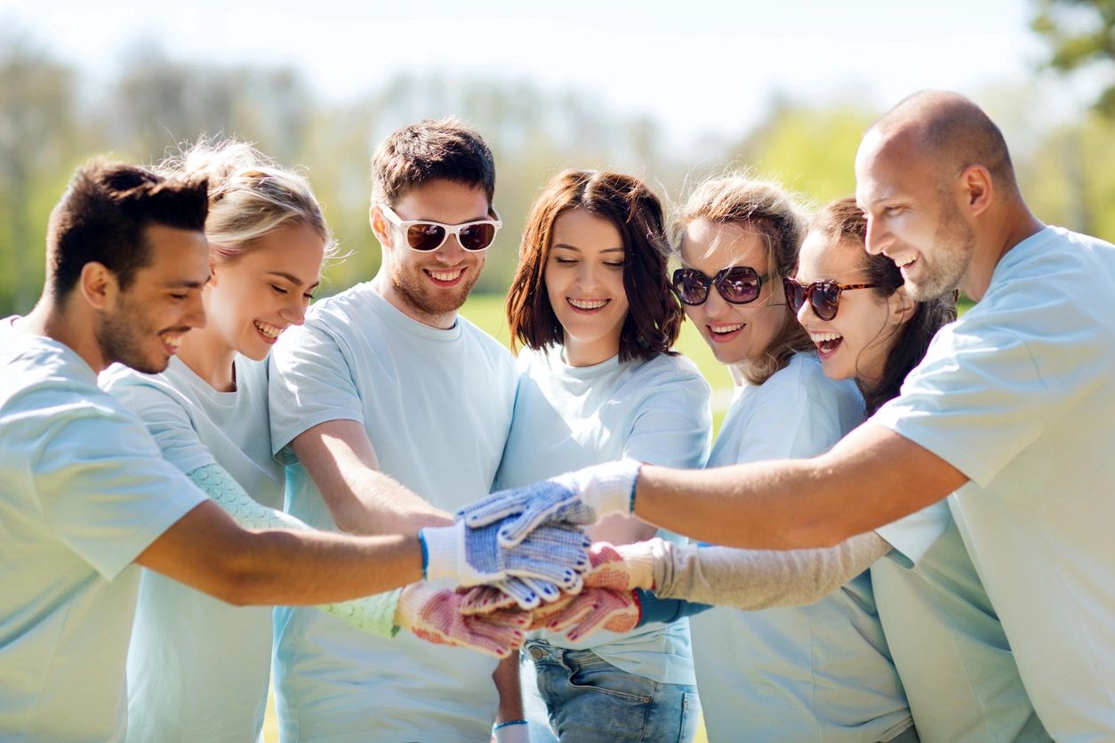 several people in matching shirts putting their hand together in the center of the circle they have arranged