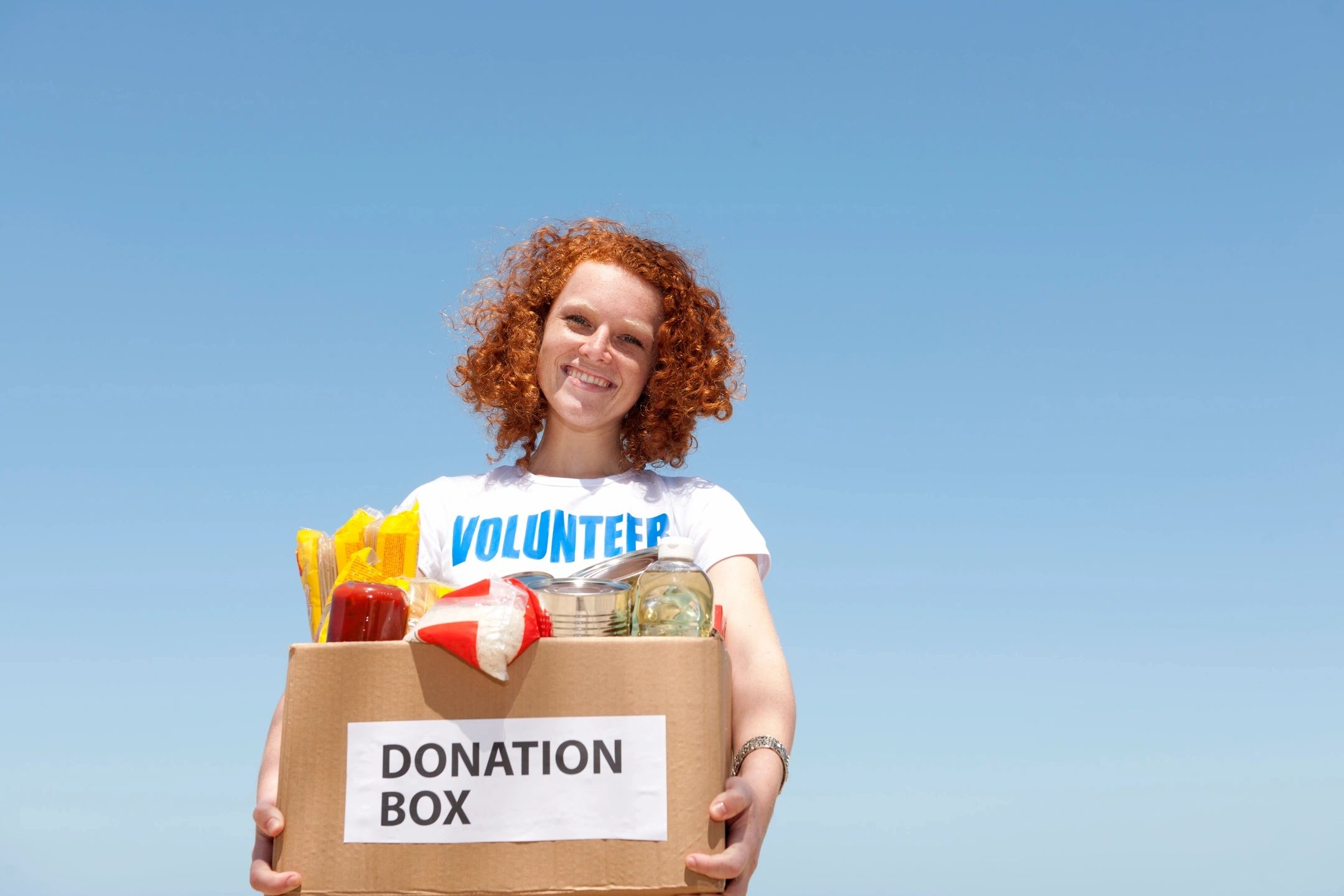 female wearing a volunteer tshirt holding a donation box